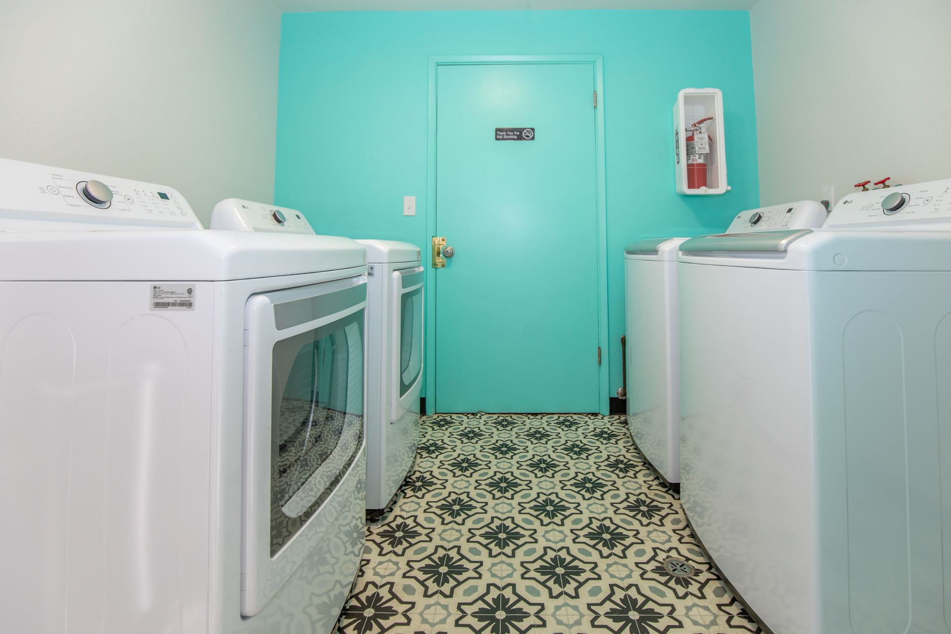A laundry room with white washers and dryers and a blue door.