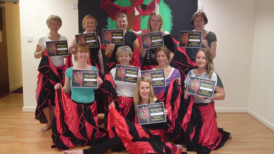 Group of women holding certificates at a Can Can themed hen party dance class, wearing red and black skirts and posing together in a studio