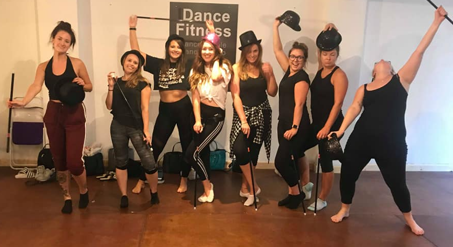 Hen party group in a dance studio performing a 1920s Charleston dance class, holding canes and top hats with a fun, lively vintage theme atmosphere