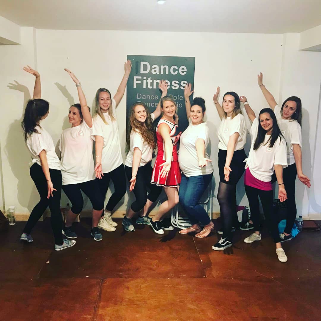 Group of women dancing and posing together at a Glee themed hen party dance class in a studio in Nottingham, smiling and celebrating with fun musical-style energy.