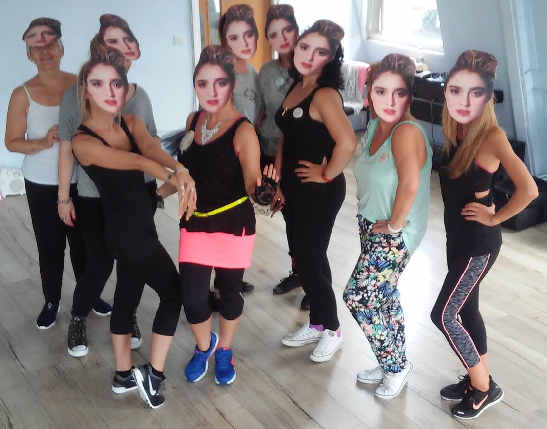 Group of women at a Madonna themed hen party dance class wearing printed face masks and fitness outfits, posing together in a dance studio with playful and confident energy.