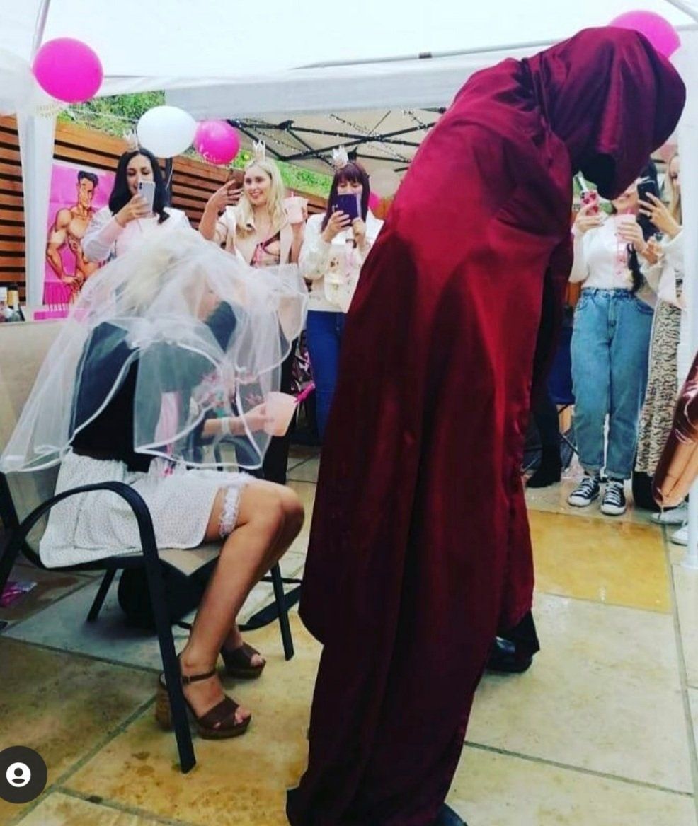 Male strip performer entertaining a hen party during a themed outdoor performance