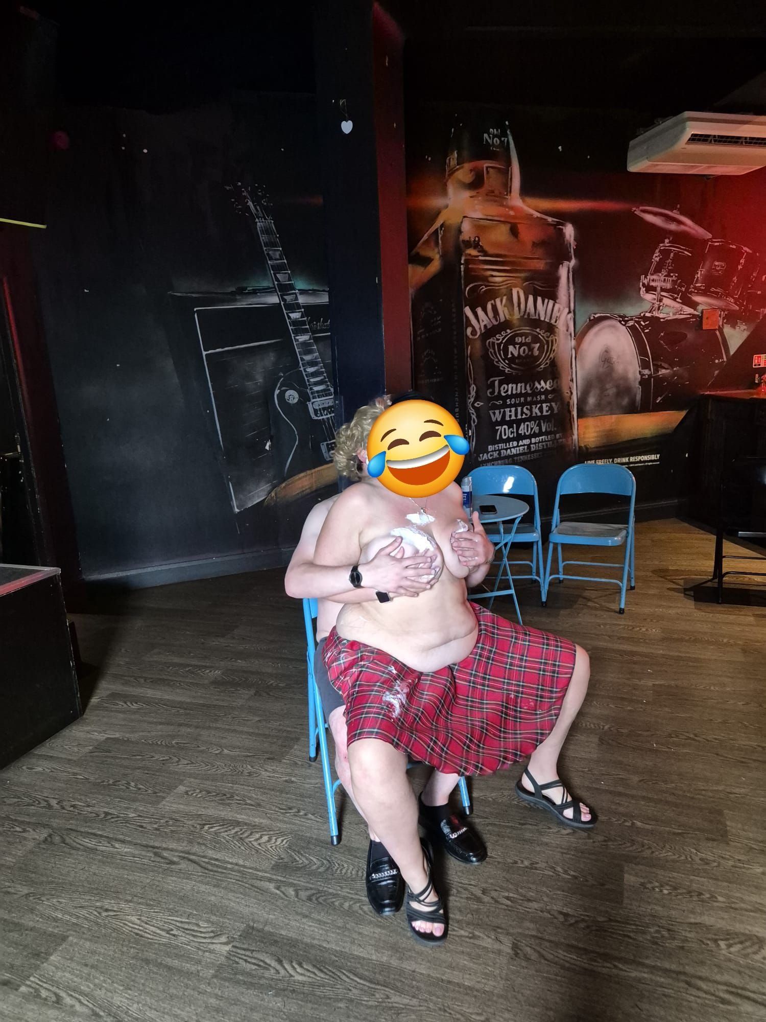 Playful plus-size entertainer “Purdy Pudding” posing confidently in a tartan skirt during a fun party performance in a nightclub venue. Based across North West England including Manchester, Liverpool and North Wales, offering cheeky, light-hearted entertainment for hen parties, stag dos and private events.