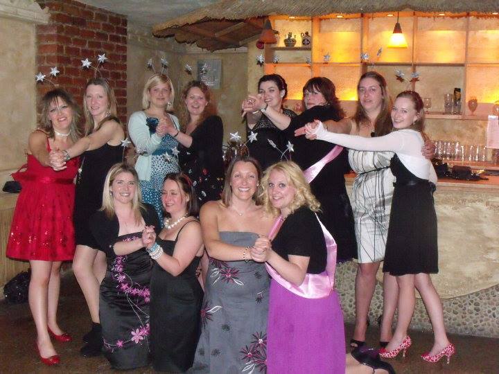 Group of women dancing together at a salsa themed hen party dance class, posing in a lively venue with fun Latin dance energy