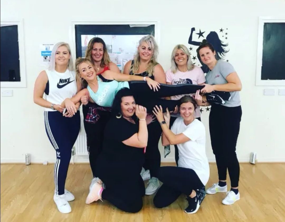 Group of women at a street dance and hip hop themed hen party dance class, posing together in a studio after a fun routine