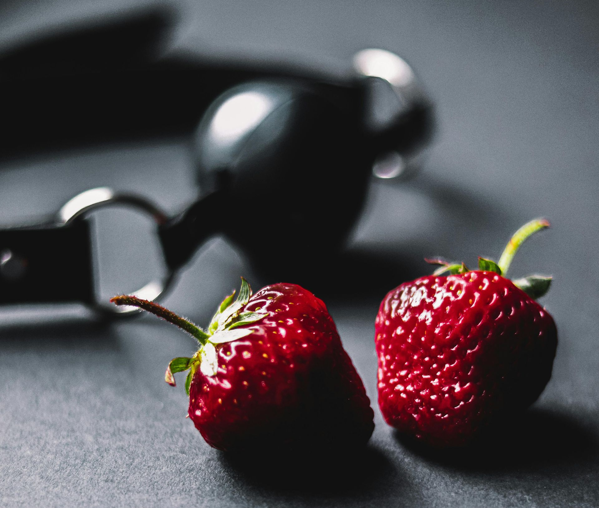 Strawberries and handcuffs symbolising playful exploration and beginner-friendly kink workshop experience in Cardiff
