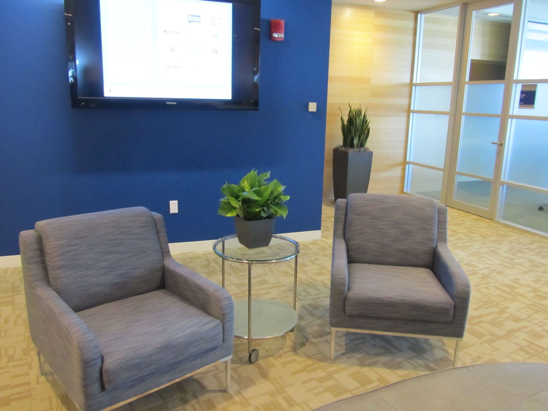 Two chairs and a table in a room with a tv on the wall