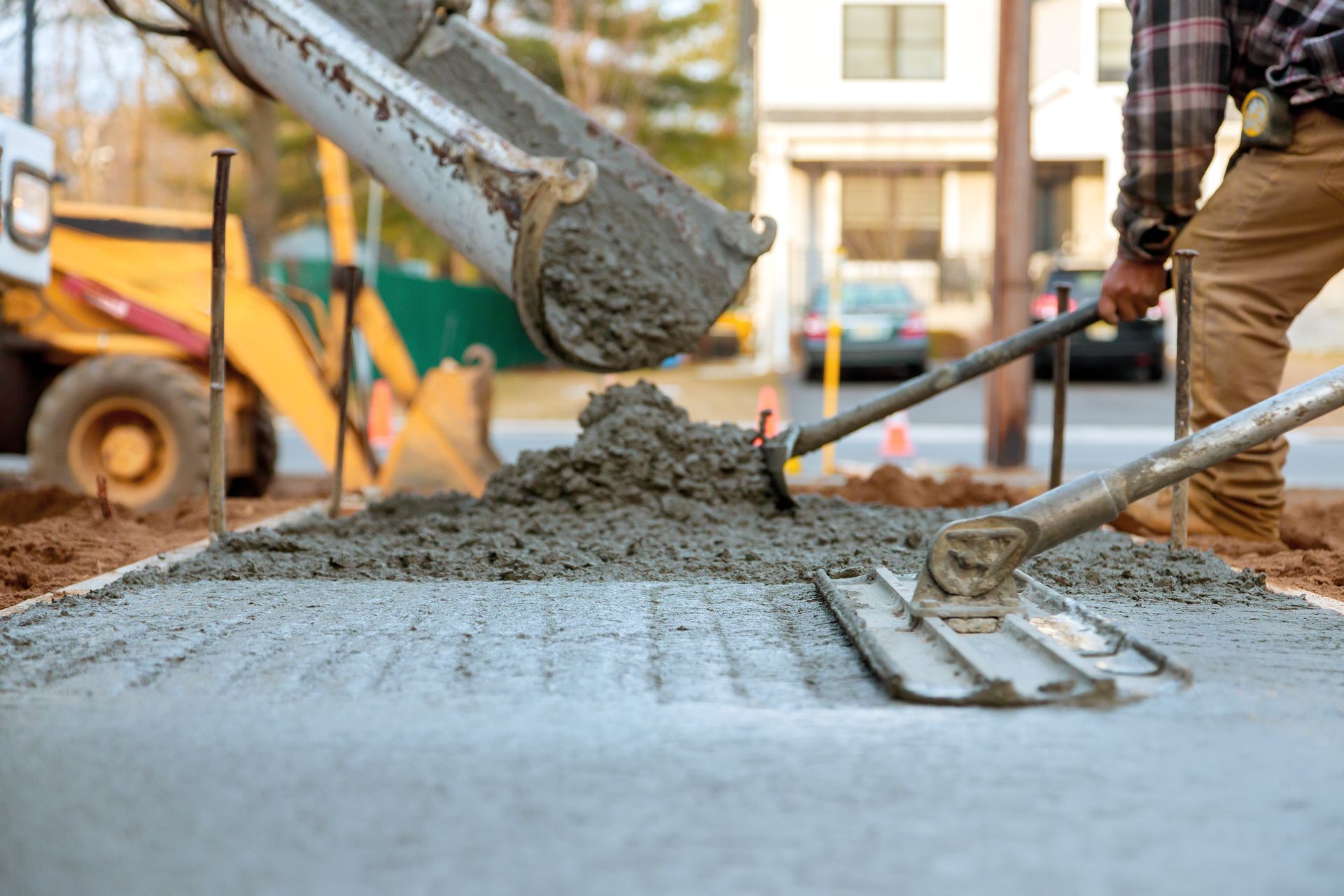 Cement being poured from a truck, workers leveling the wet concrete on a street.