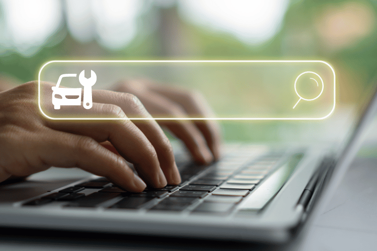 Hands typing on a laptop with a glowing search bar and car repair icon overlay