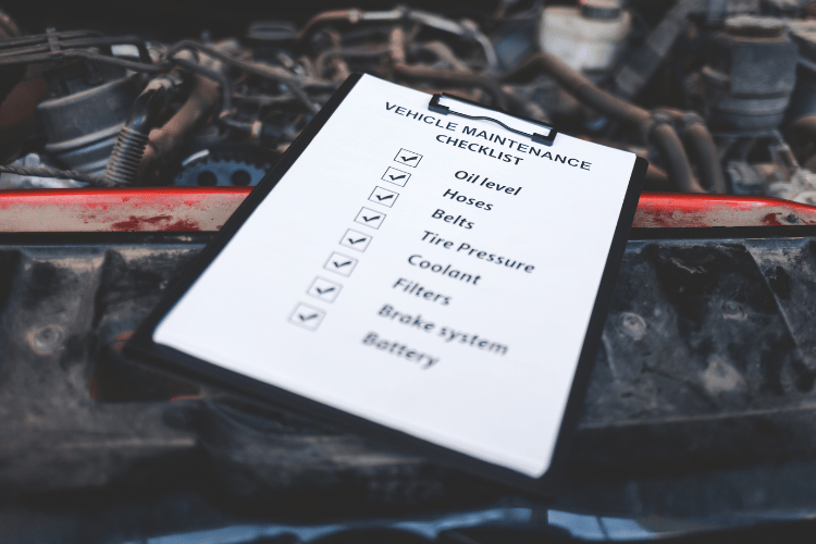 Checklist on a clipboard in a car engine bay, with several items checked off.