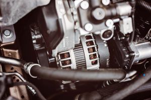 Close-up of a car engine with an alternator and hoses, showing metallic components