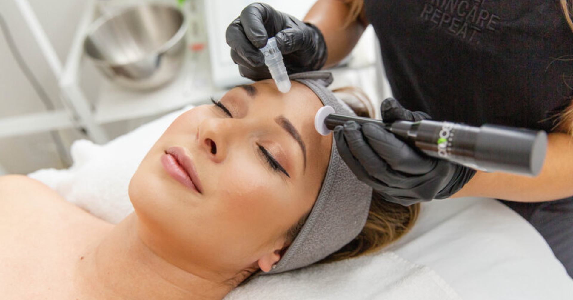 Woman receiving cosmetic procedure on forehead in a clinic. Aesthetican wearing gloves holds tools.