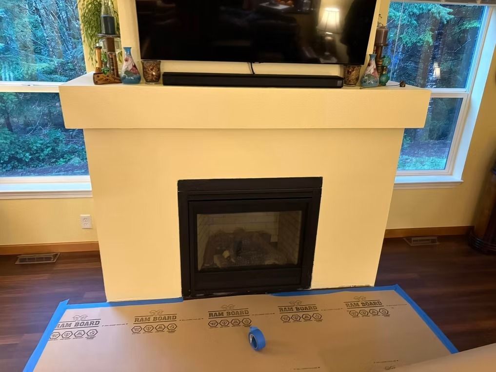 A fireplace with a black firebox and a white mantle, with a TV above.