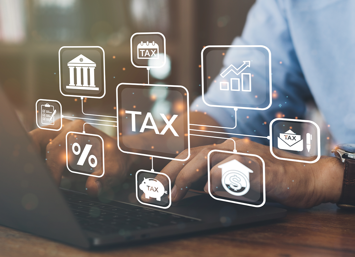 A person using a laptop with glowing, digital icons representing tax, finance, and banking services overlaid on the screen.