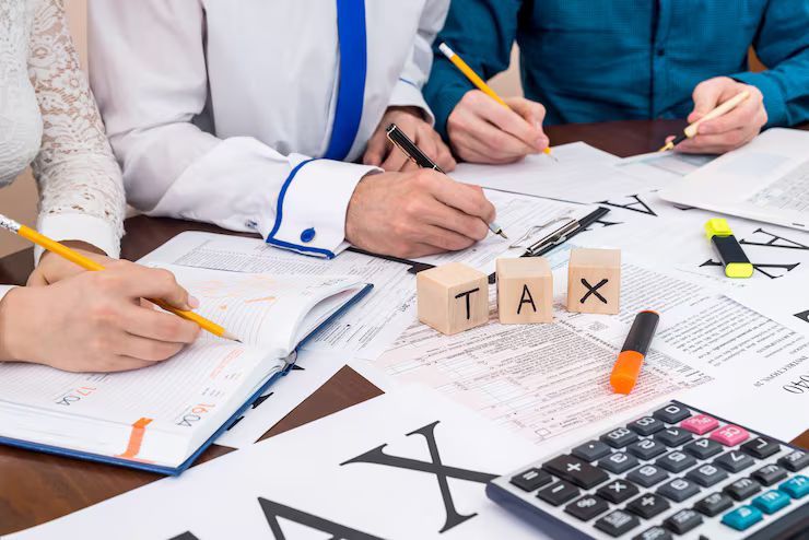 People writing on tax forms with pencils,