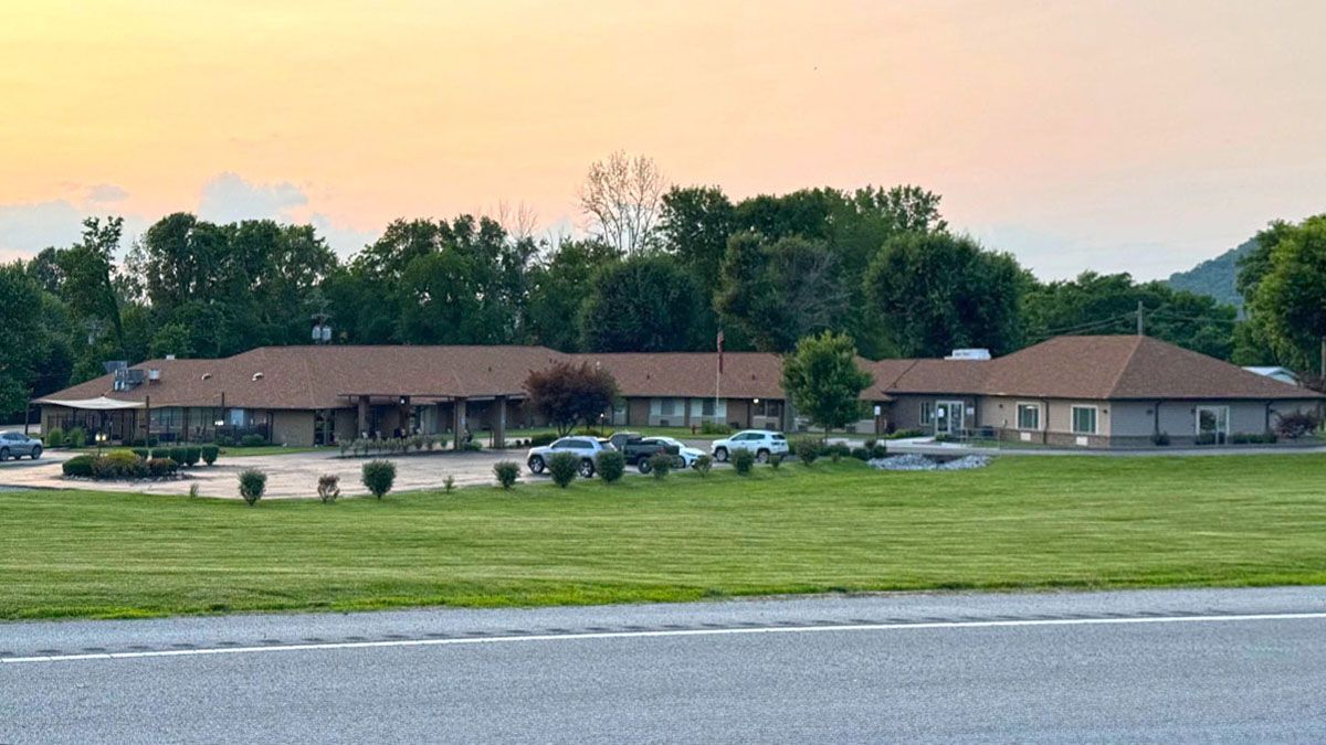 A large motel with a lot of cars parked in front of it.