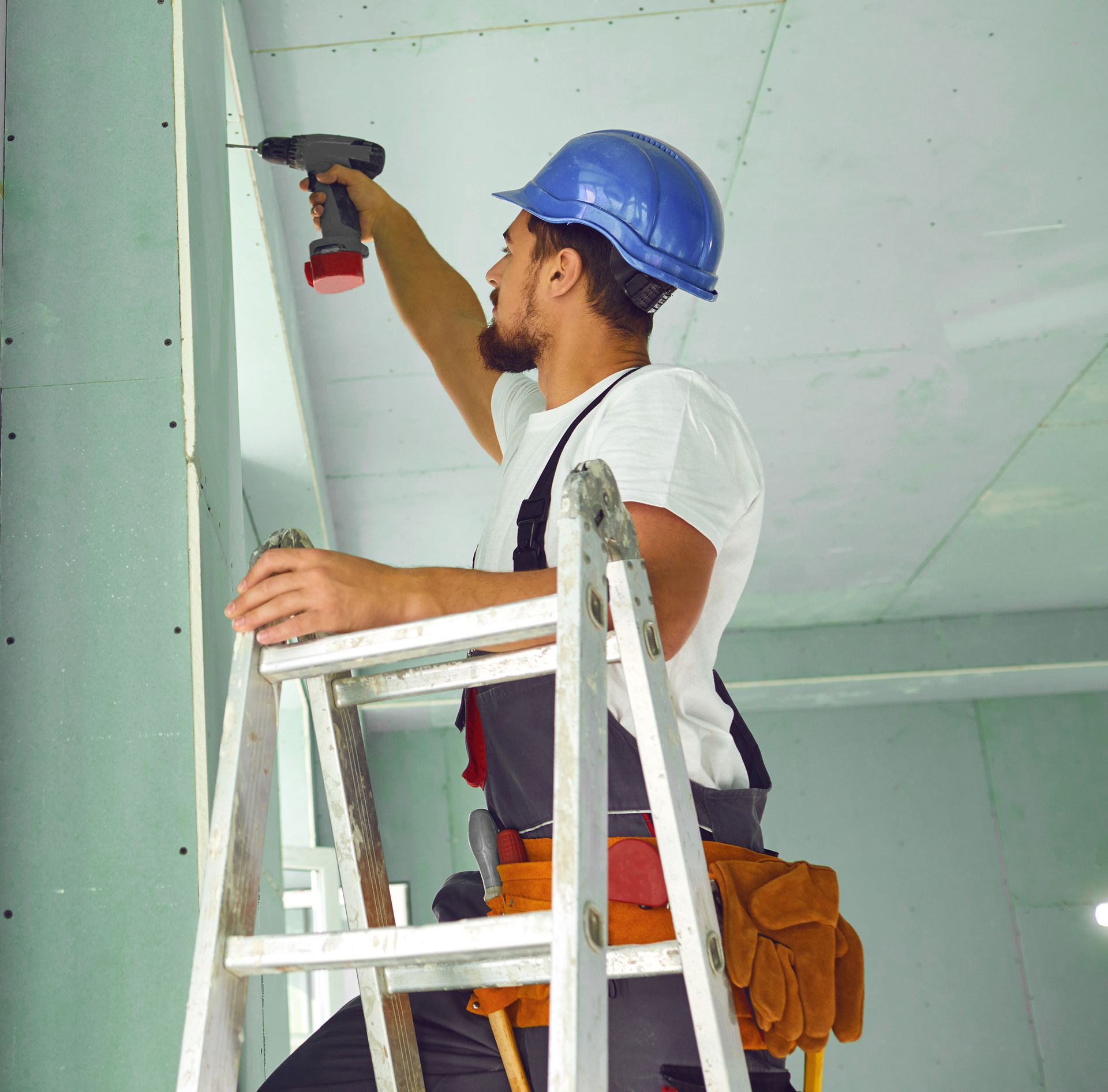 A man is measuring a wall with a tape measure.