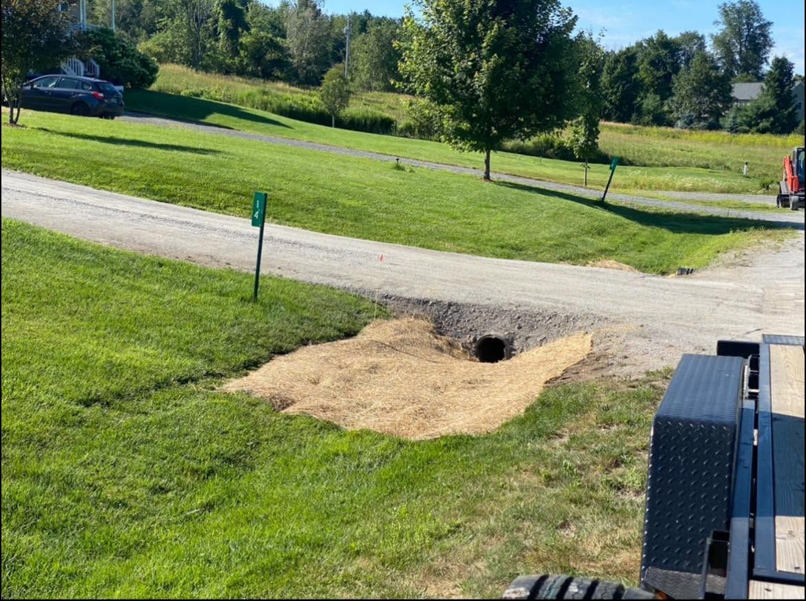 Small tunnel entrance in a grassy park beside a gravel path and bench.