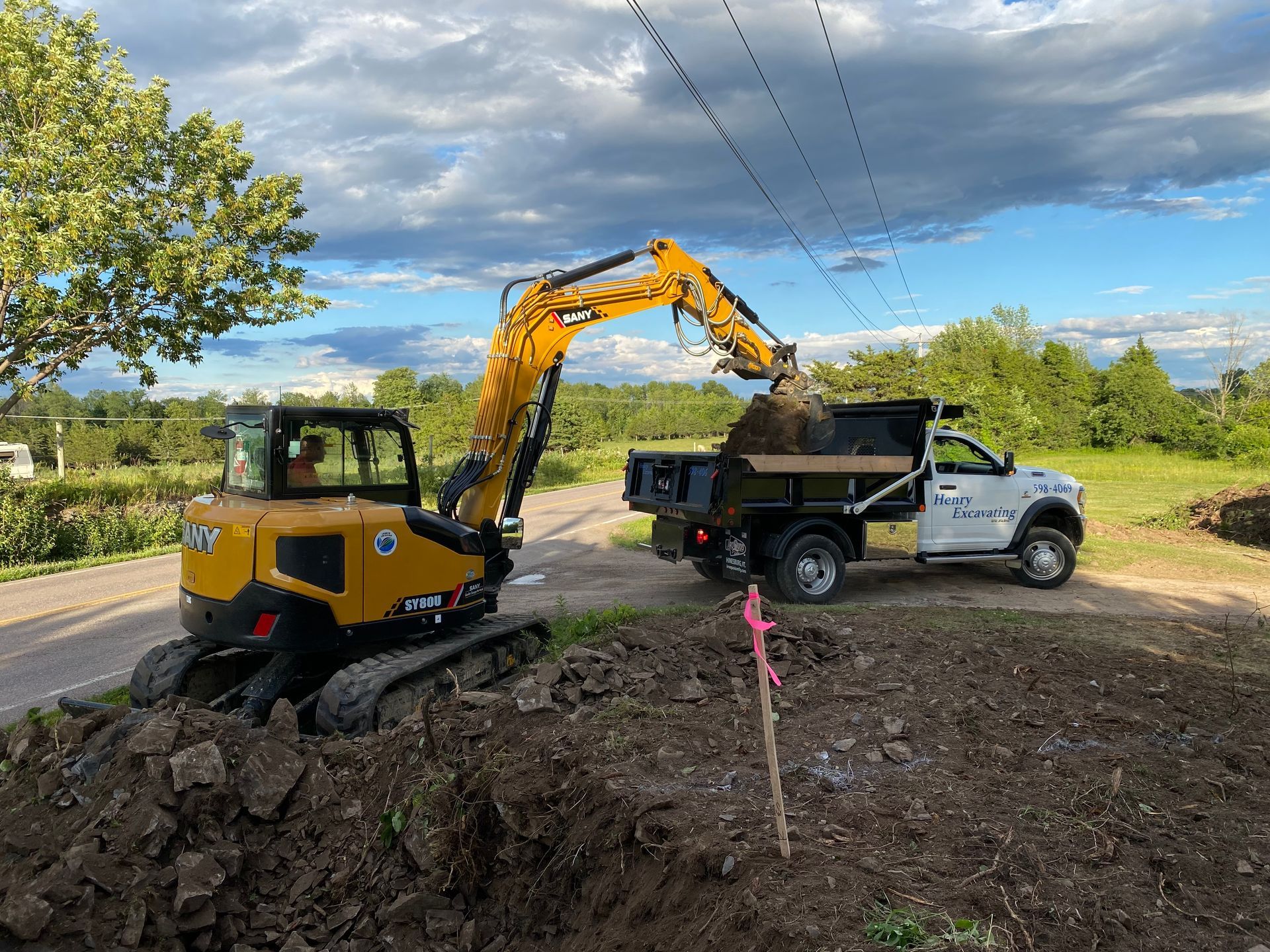 Yellow excavator spreading gravel on a forest road under construction