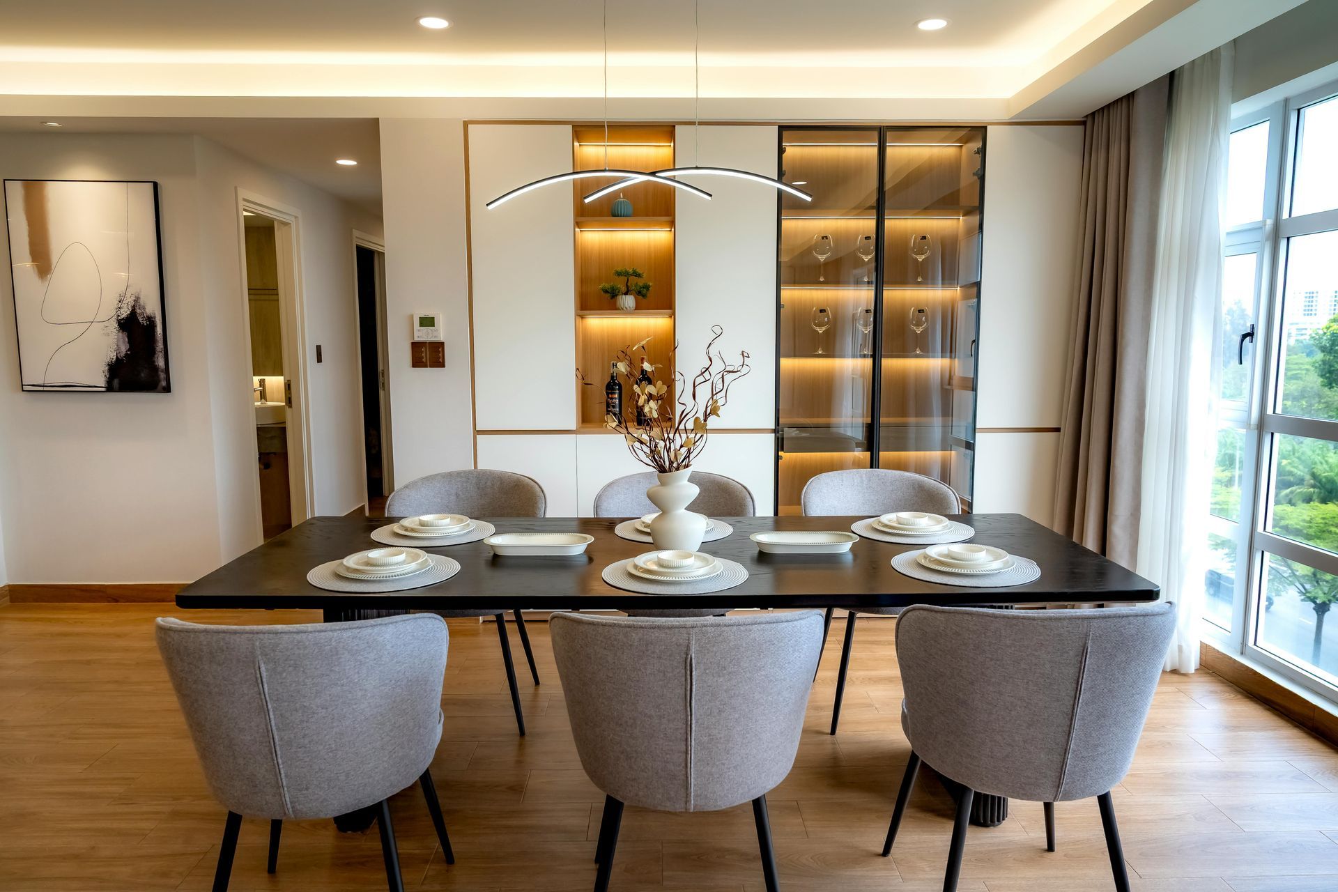 Dining room with table set for six, light gray chairs, and built-in shelves.