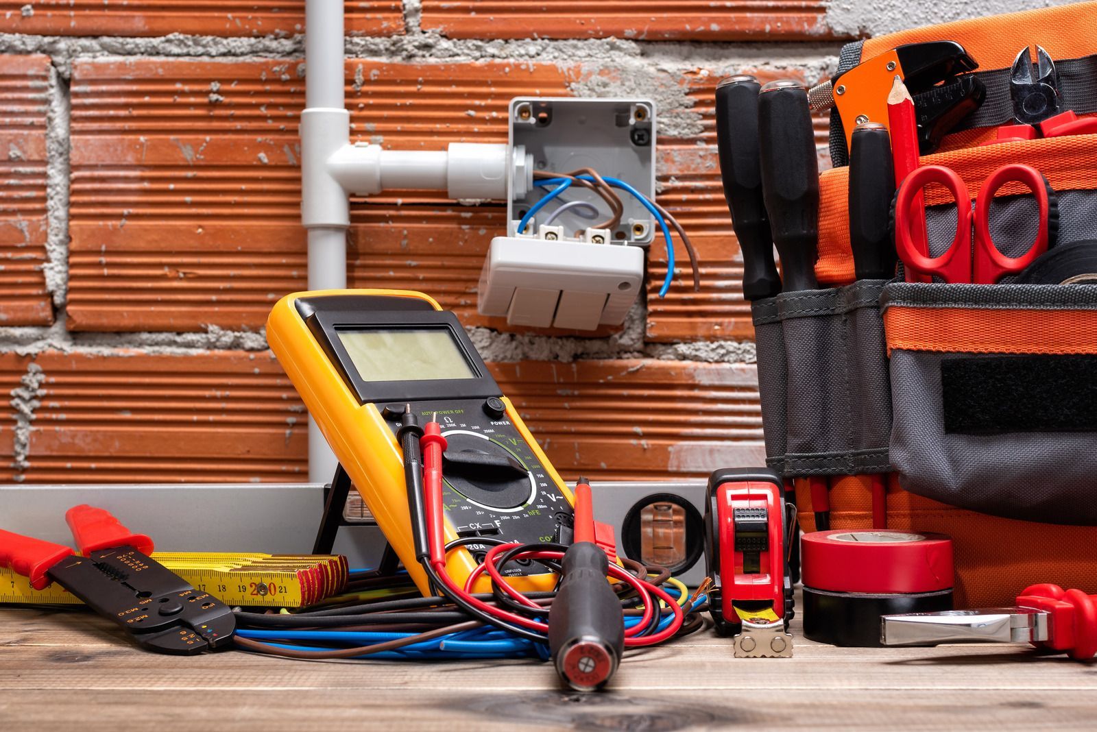 A bunch of tools are sitting on a wooden table in front of a brick wall.