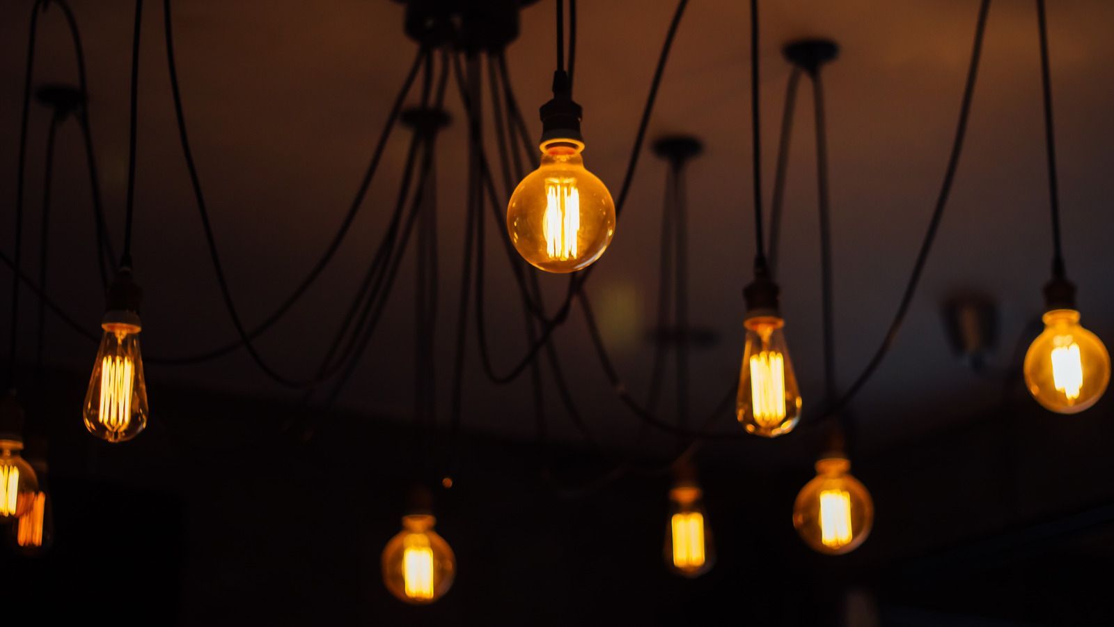 A bunch of light bulbs hanging from the ceiling in a dark room.