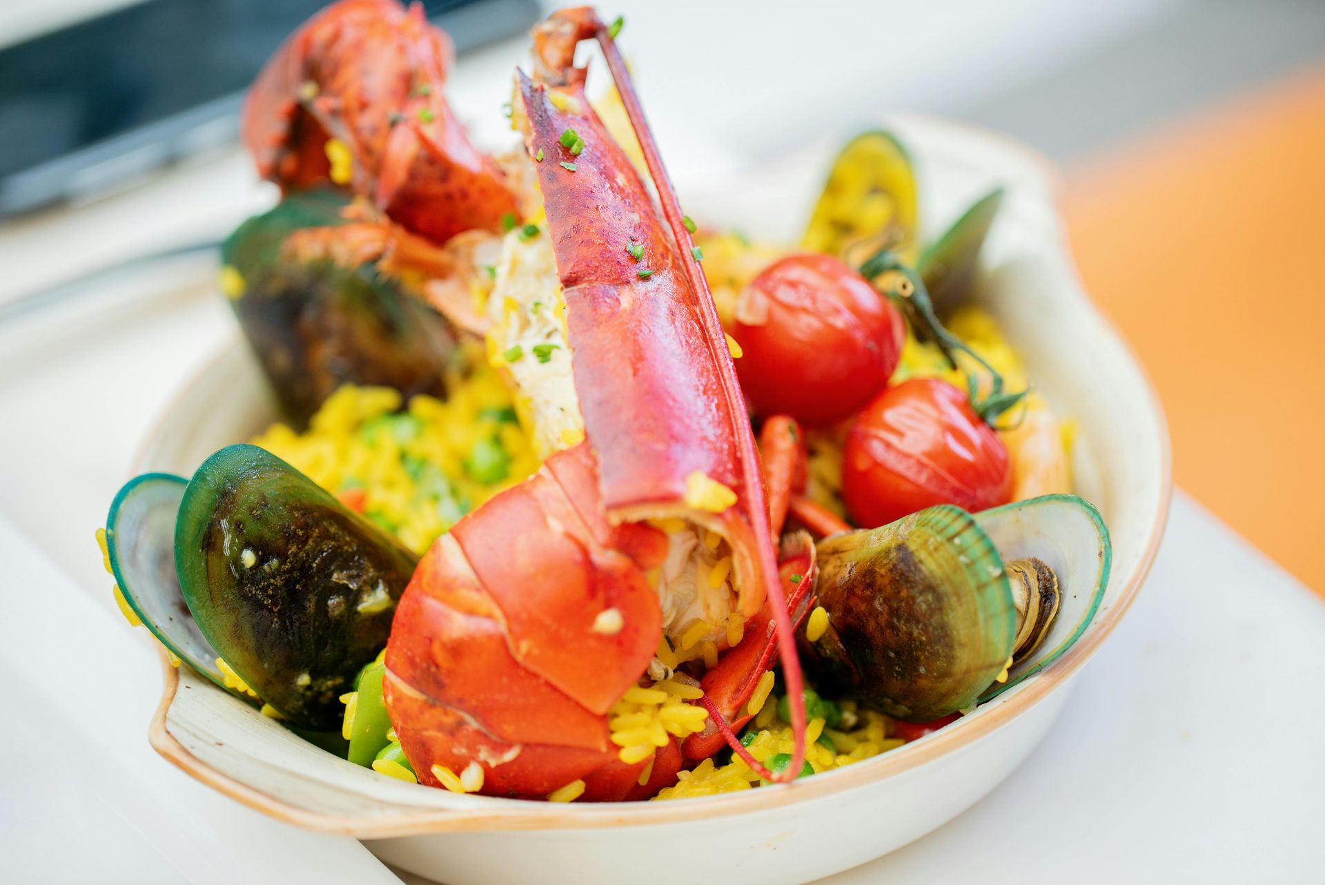 A close up of a plate of food with a lobster on top.
