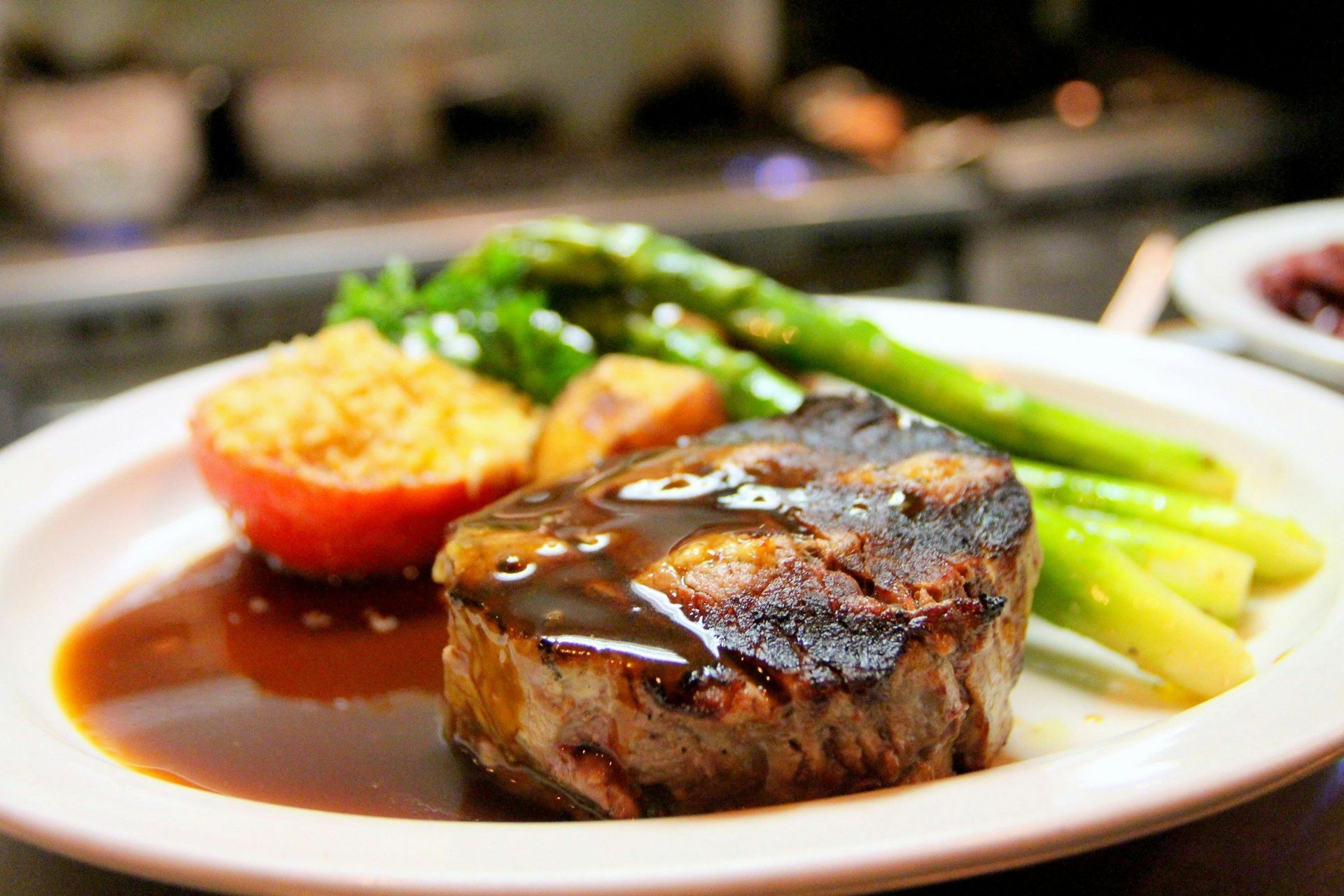 A white plate topped with a steak , asparagus , mashed potatoes and gravy.