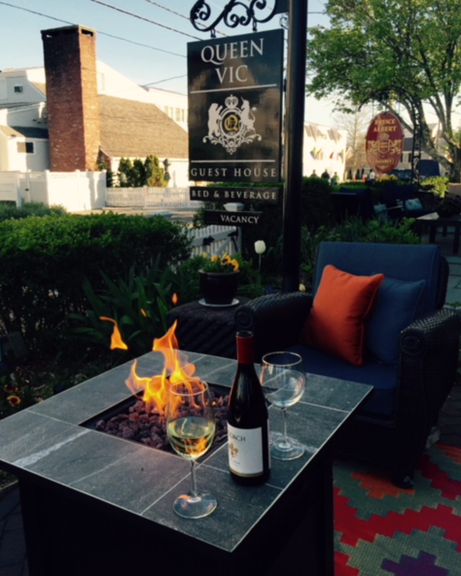 A bottle of wine sits on a table in front of a queen vic sign