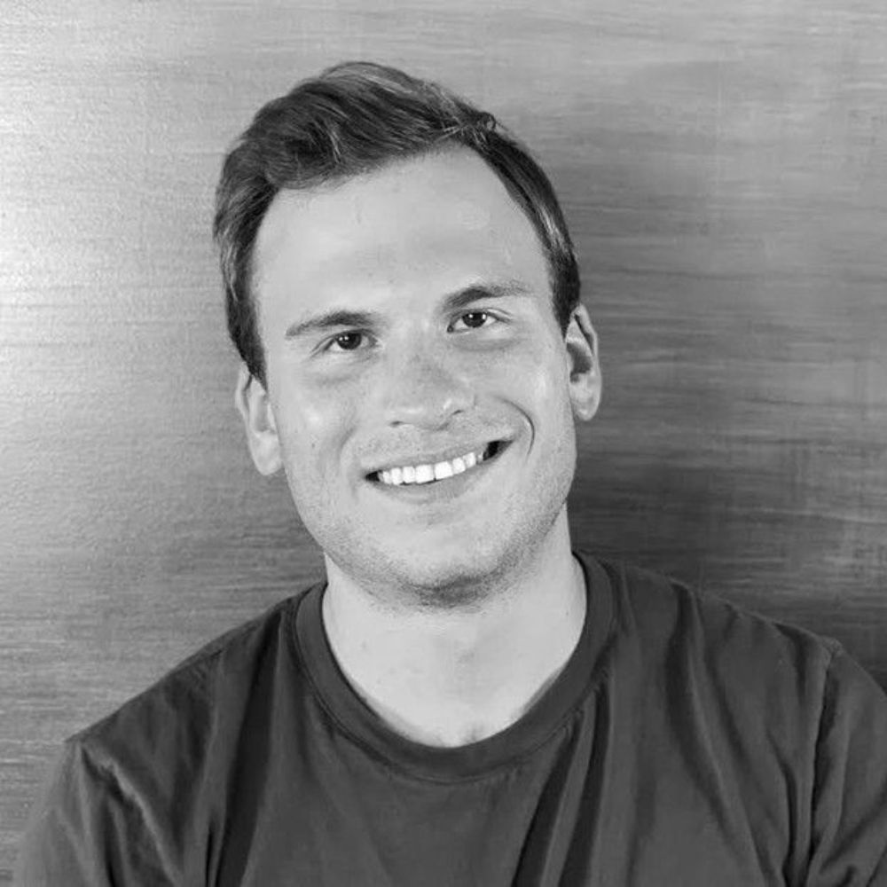 Smiling man in a dark T-shirt against a plain gray background