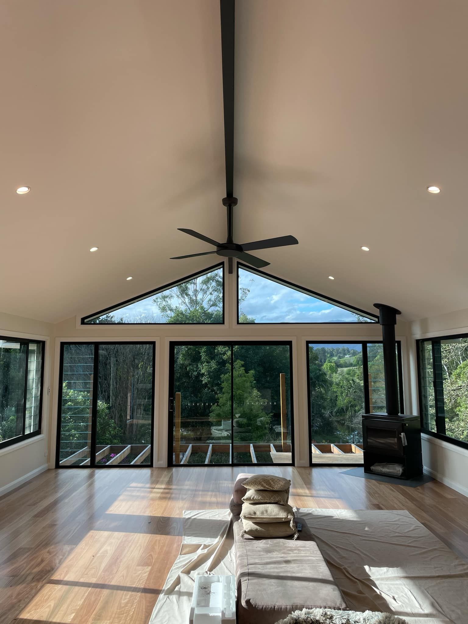 Bright, open room with large windows overlooking a green landscape, wooden floors, and a ceiling fan — Stuart Pearce Electrical In Coffs Harbour, NSW