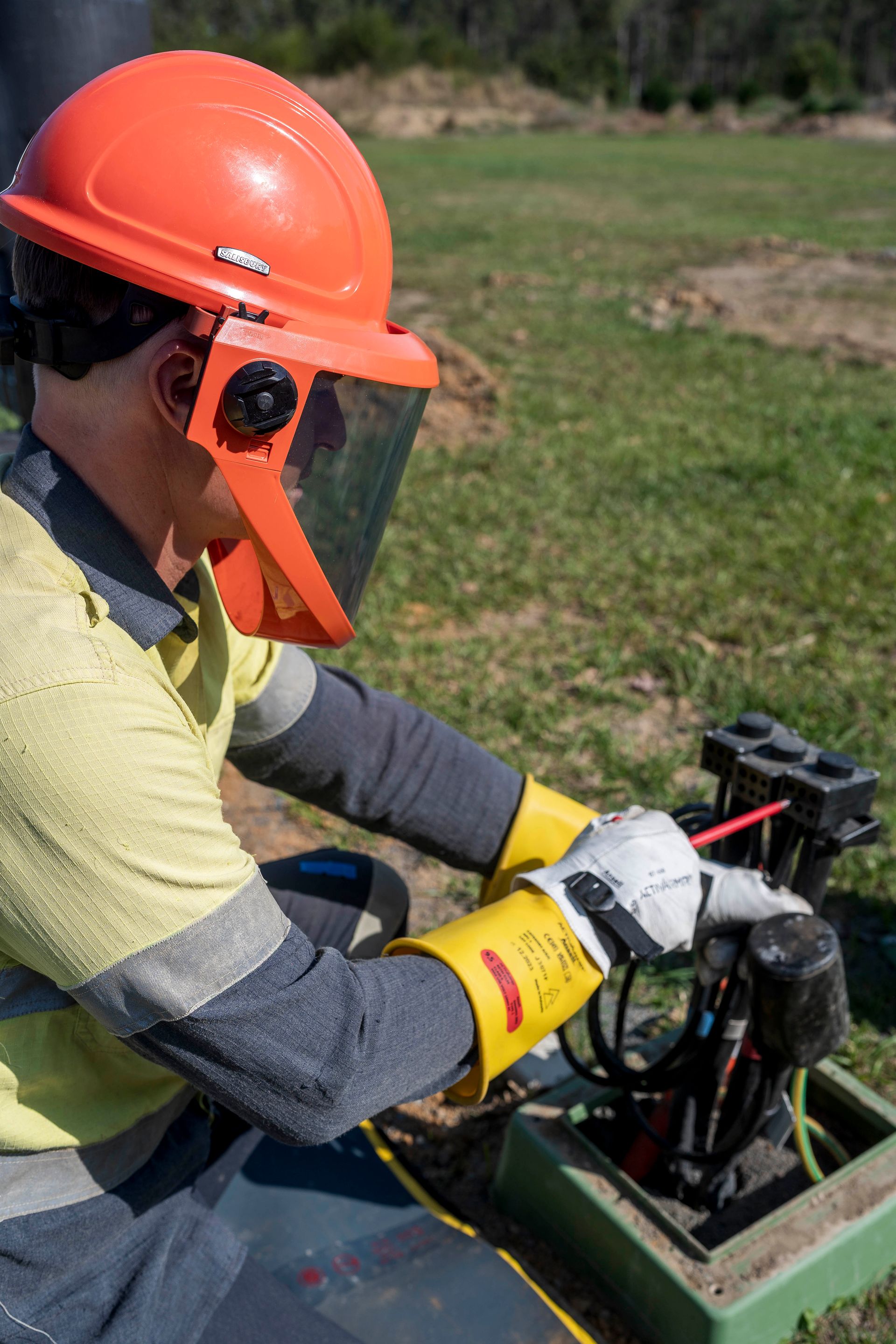 Worker in protective gear inspects equipment outdoors — Stuart Pearce Electrical In Bellingen, NSW