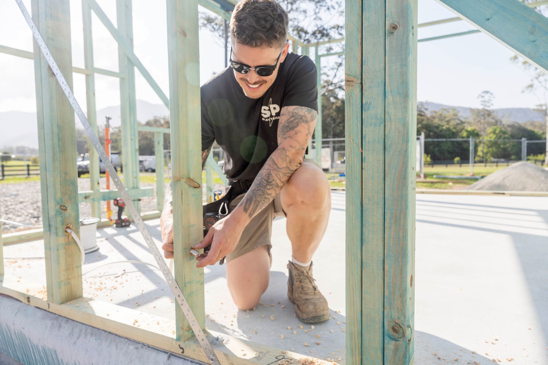 Carpenter measures a wooden frame at a construction site — Stuart Pearce Electrical In Coffs Harbour, NSW