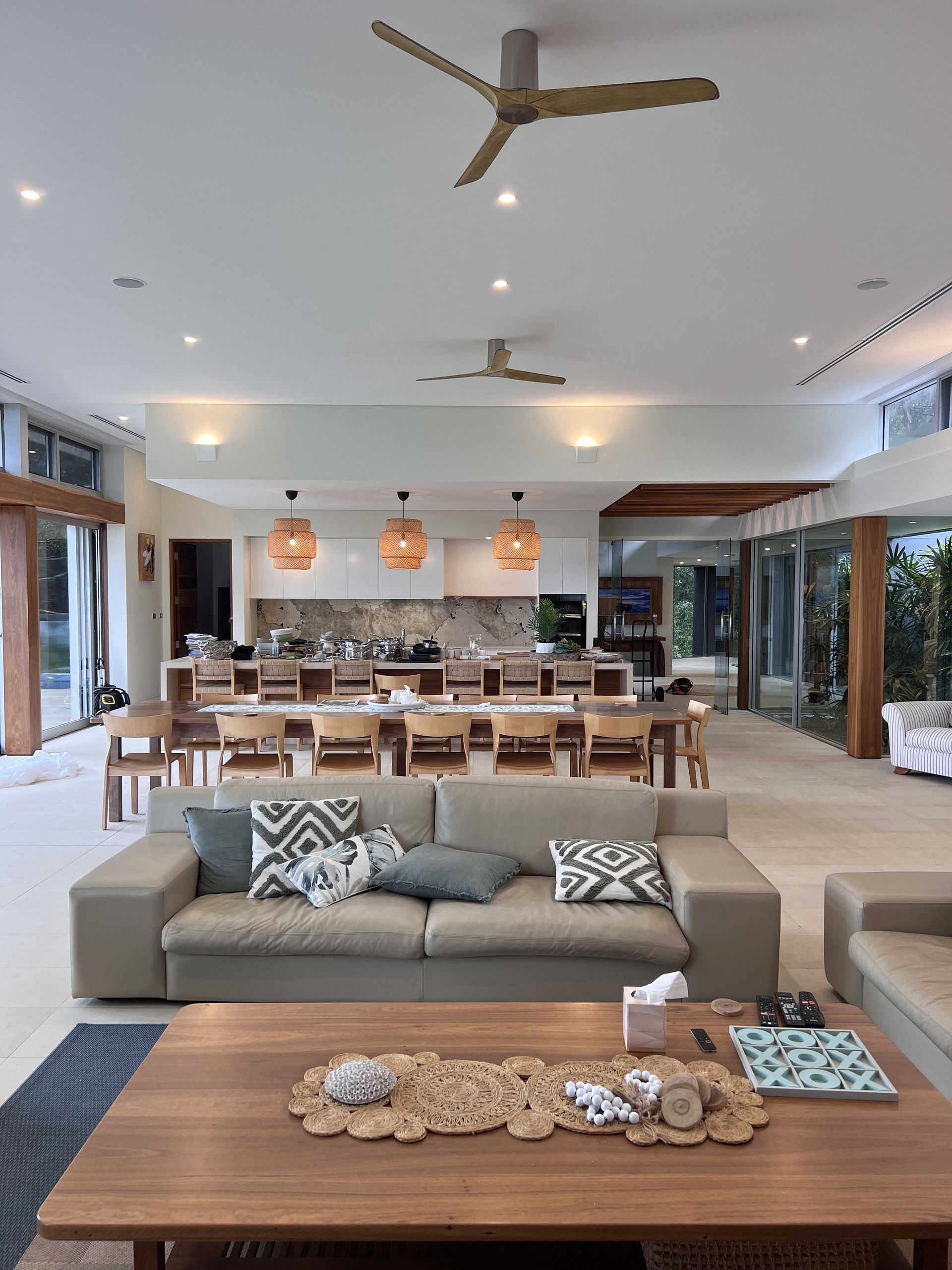 Spacious open-concept living area with a sofa, kitchen, dining table, and ceiling fans — Stuart Pearce Electrical In Coffs Harbour, NSW