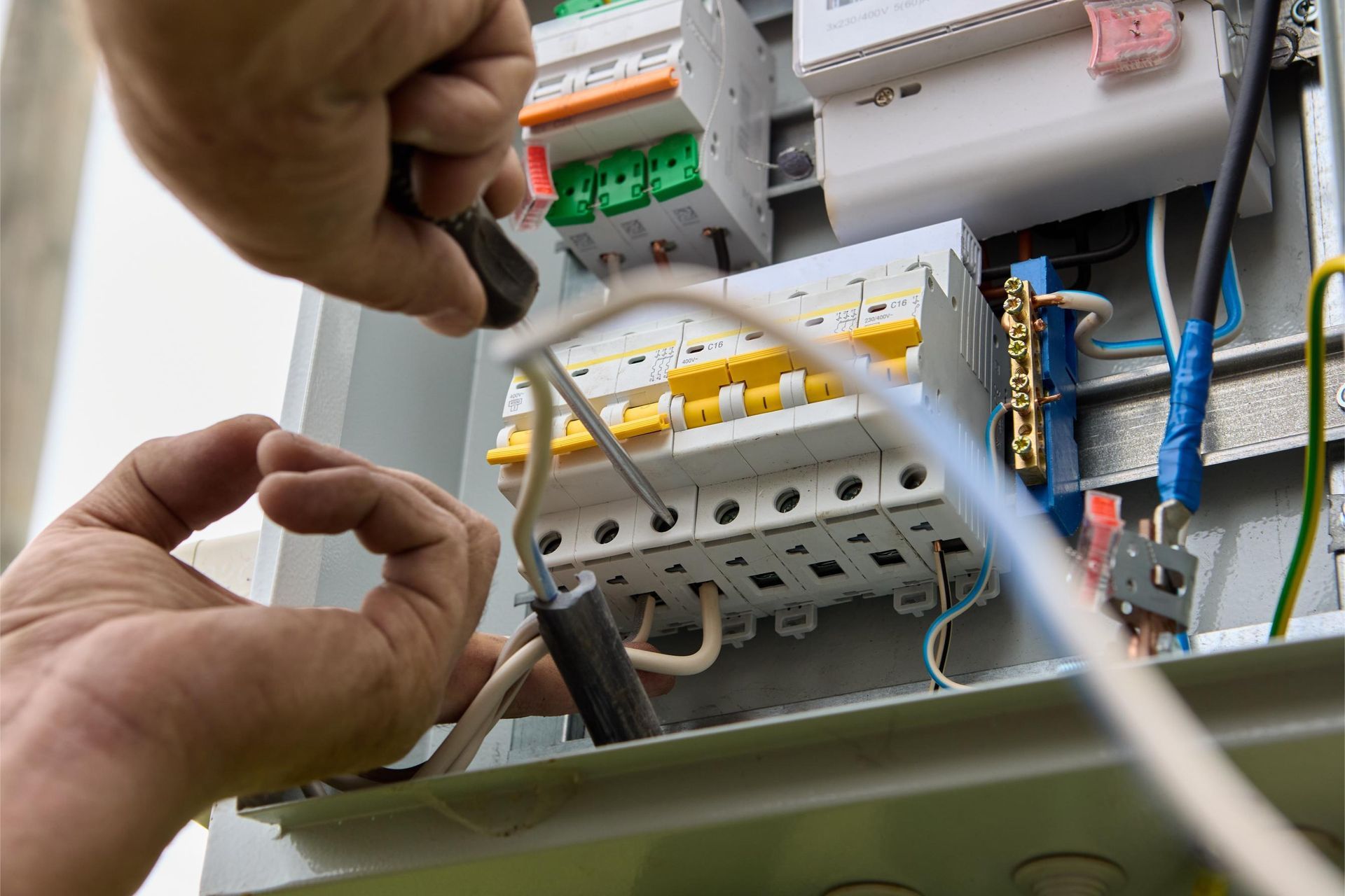 a person is working on an electrical box with a screwdriver .