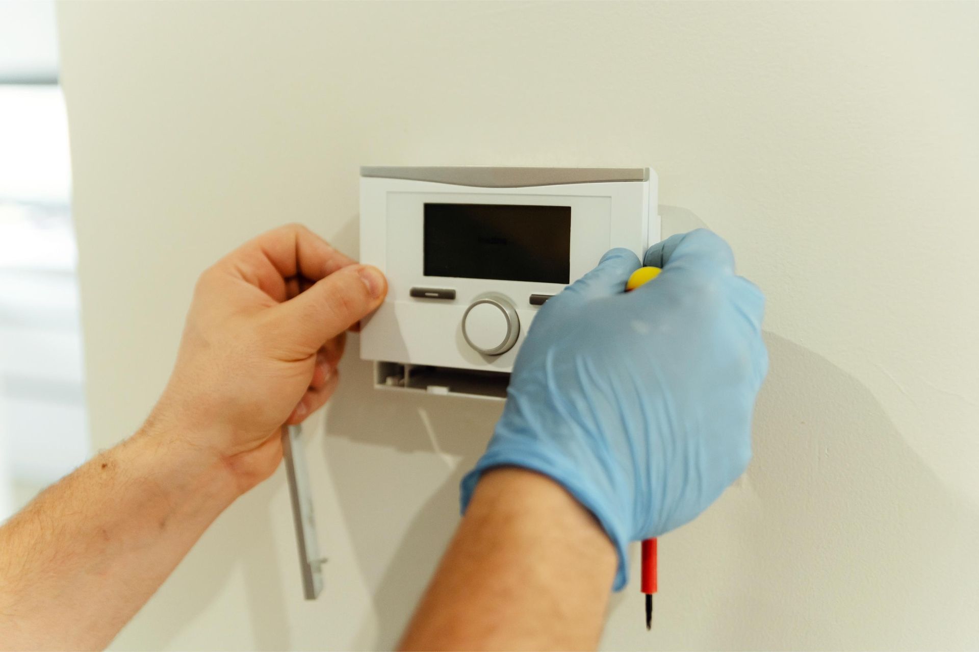 an electrician is working on an electrical box with a multimeter .