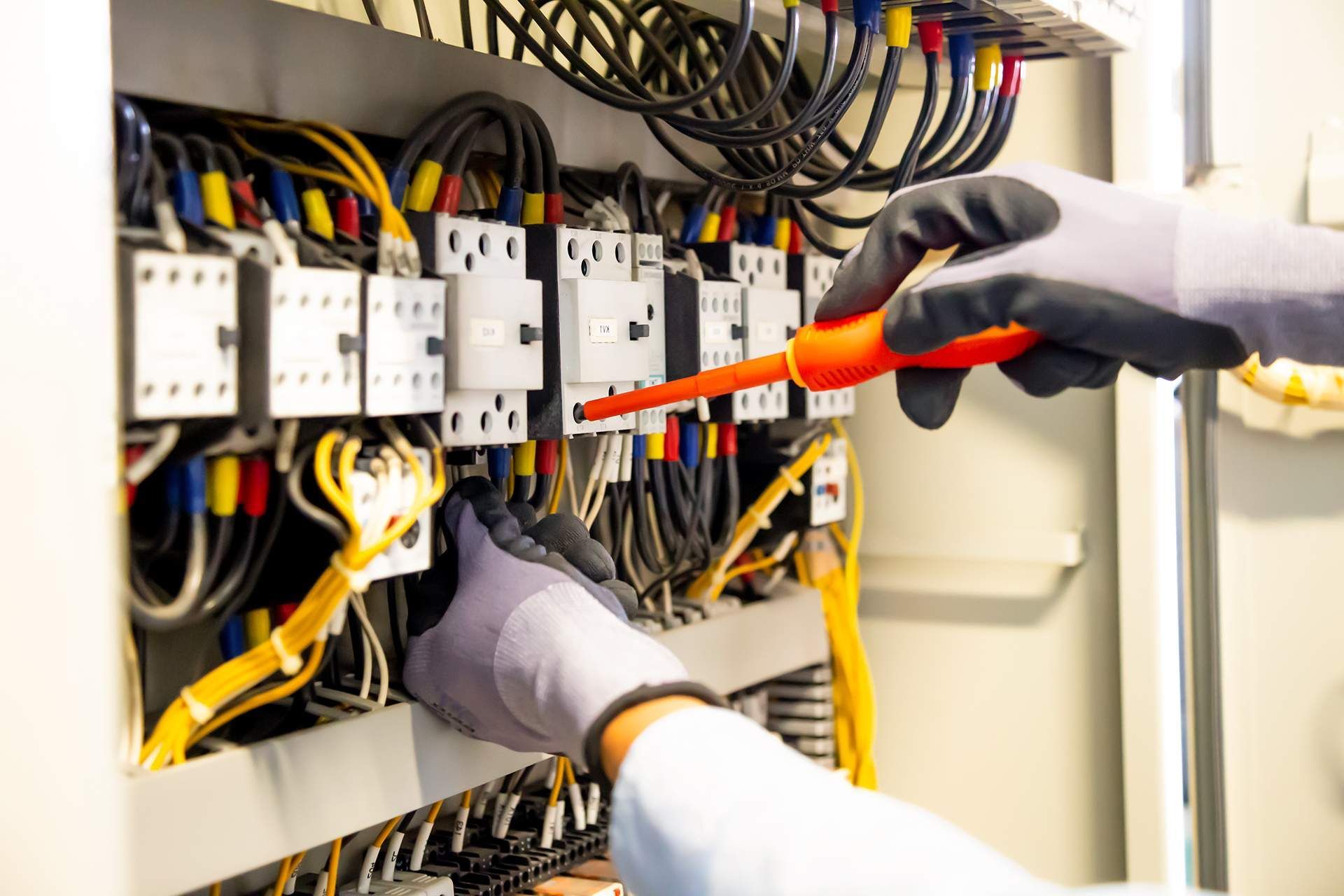 an electrician is working on an electrical box with a screwdriver .