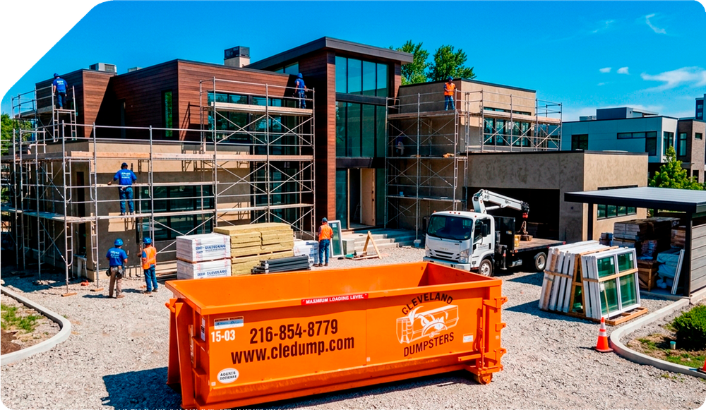 Construction site with scaffolding around a modern building and an orange dumpster in front
