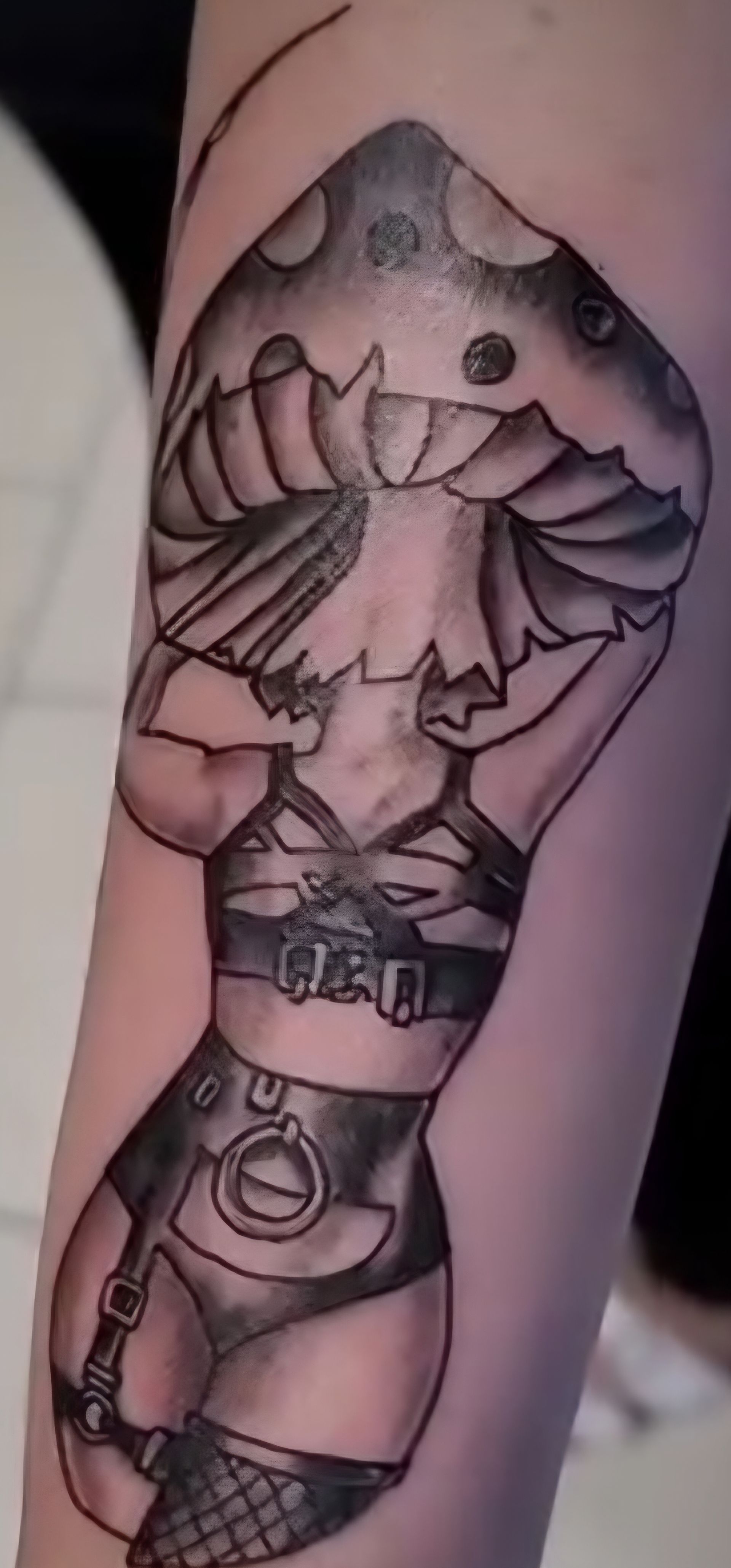 Tattoo of a mushroom with a woman's body wearing lingerie, on an arm.