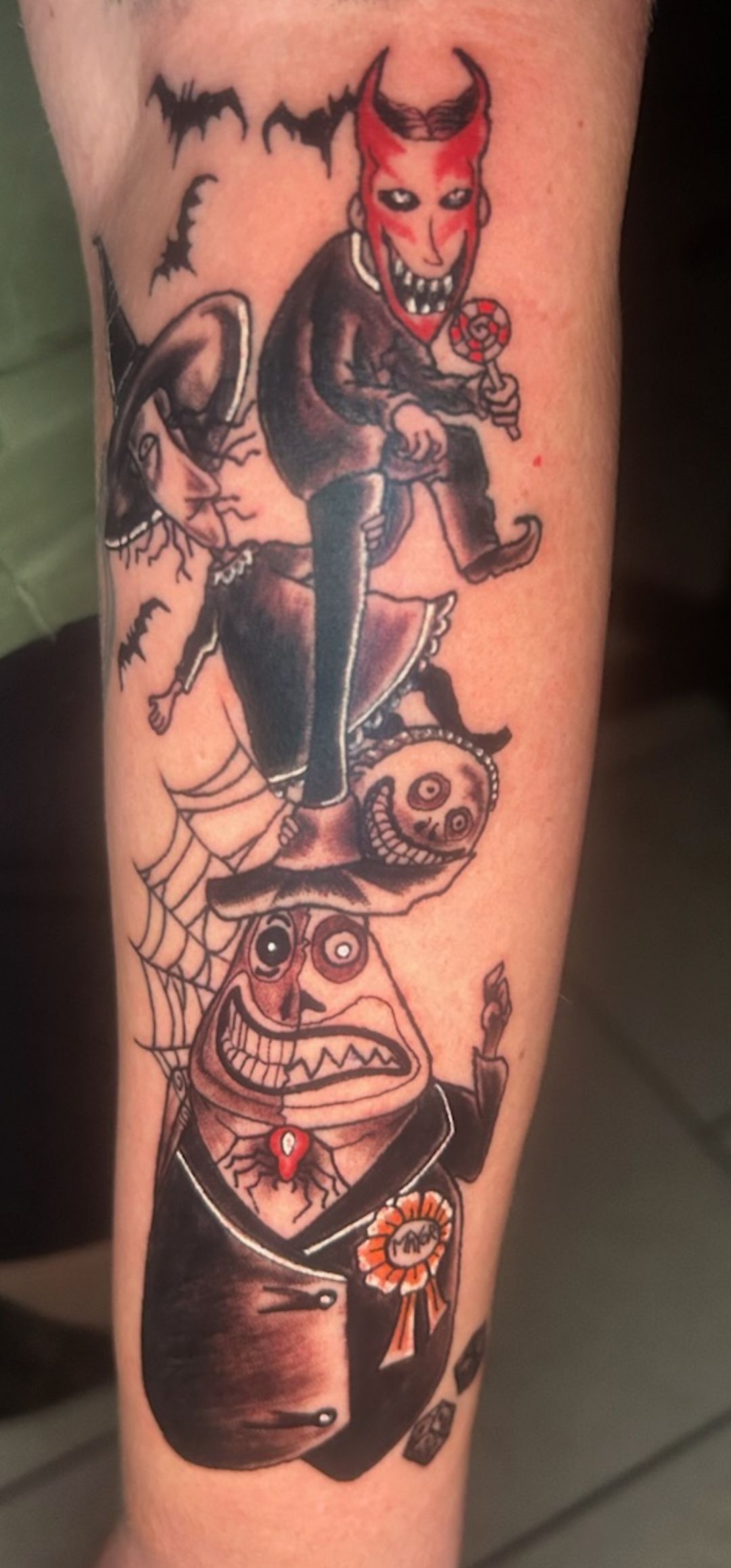 Tattoo of a red-horned devil riding a cartoon rocket over a grinning skull with web and cobweb details