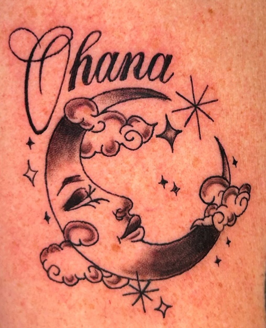 Black crescent moon tattoo with clouds, stars, and the name “Chana” in cursive.