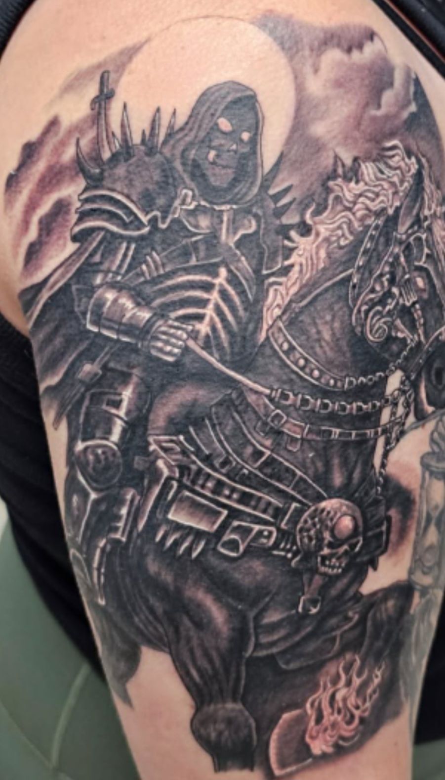 Black-and-gray tattoo of a hooded armored warrior riding a horse, with ornate details and swirling background