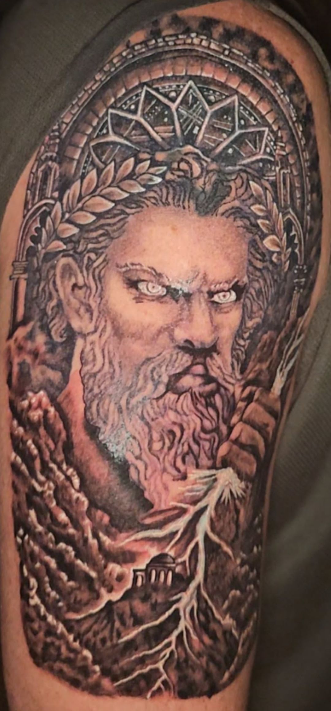 Ornate tattoo of a stern, bearded figure with glowing eyes framed by intricate patterns