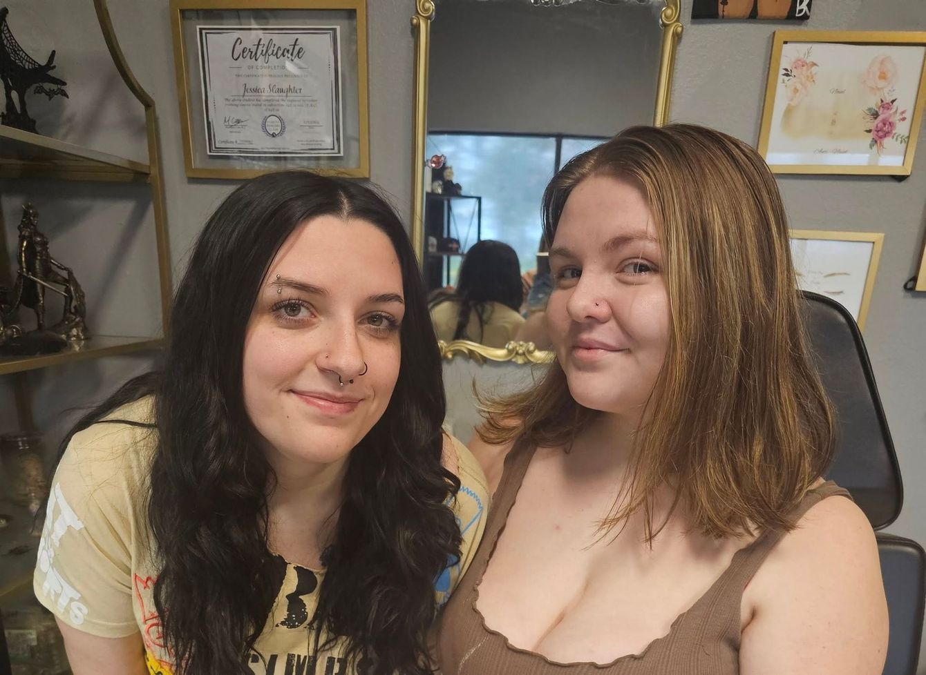 Two women are posing for a picture in front of a mirror.