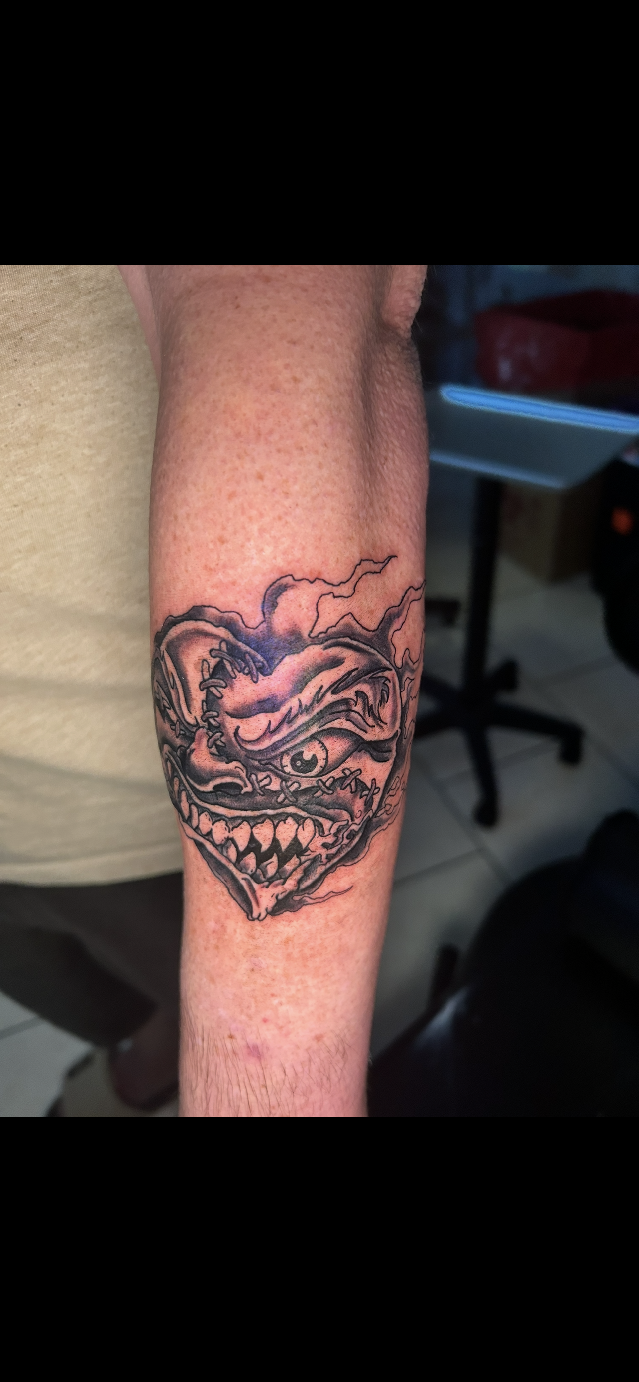 Tattoo of a heart-shaped design on a person's arm. It's a black and gray intricate pattern.