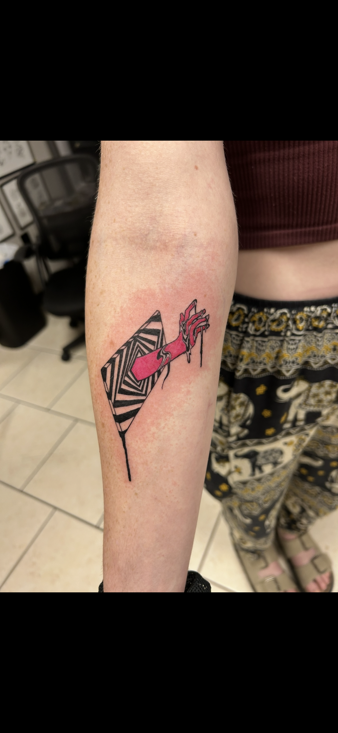 Tattoo on an arm. Features a zebra-striped design with a pink dripping shape.