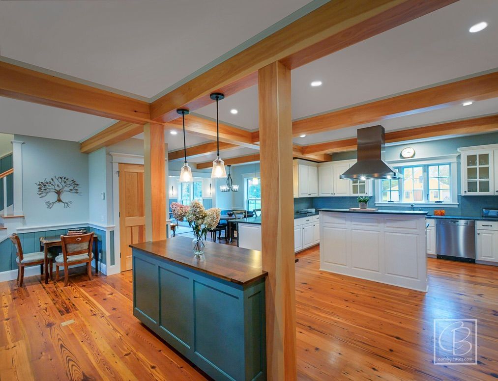 Bright open kitchen and dining area with blue walls, wood floors, and exposed beams