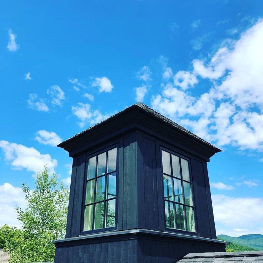 Black lookout tower against a bright blue sky with scattered clouds