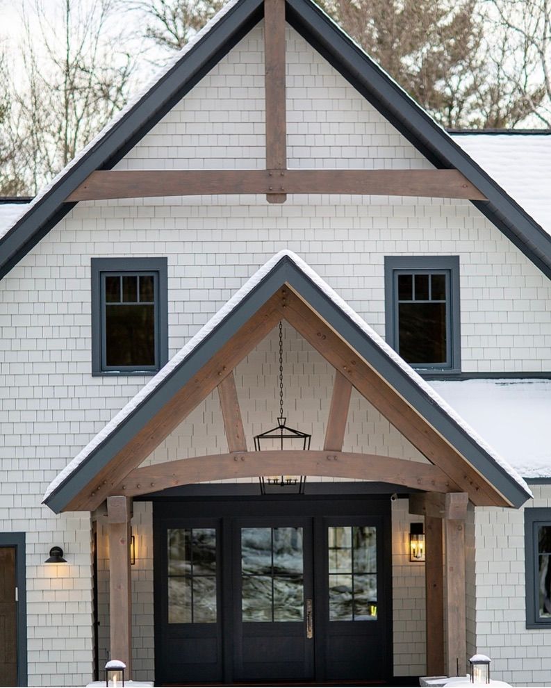 Gray two-story house with red-trim garage doors and patio pots under a blue sky