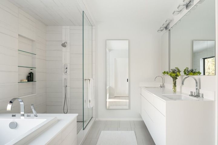 Bright white modern bathroom with bathtub, glass shower, double vanity, and flowers on the counter
